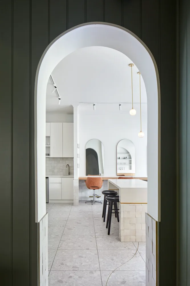 Sage-green arched doorway into the white styling room at Frankie Salon South Yarra