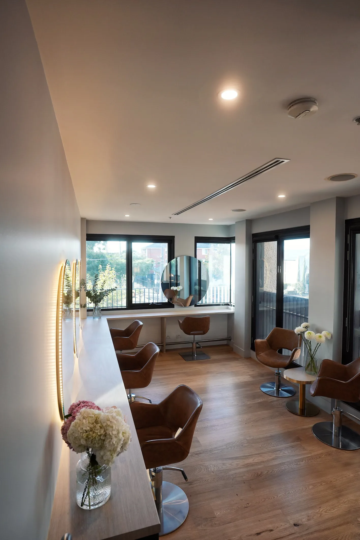 Richmond salon — styling chairs by window, round mirror, fresh flowers